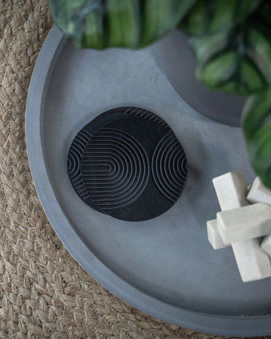 Black leather coasters featuring modern arch pattern debossed on the surface.