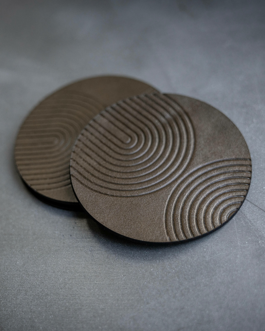 Olive green leather coasters featuring modern arch pattern debossed on the surface.