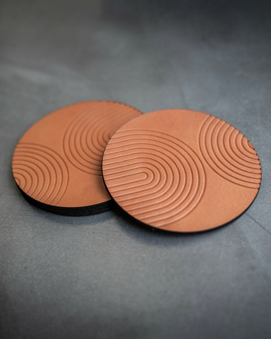 Tan leather coasters featuring modern arch pattern debossed on the surface.