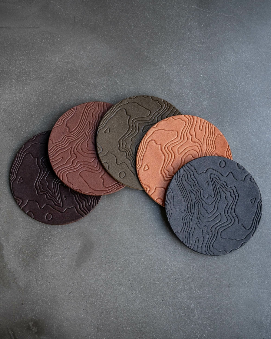 leather coasters featuring a topographic pattern debossed on the surface.