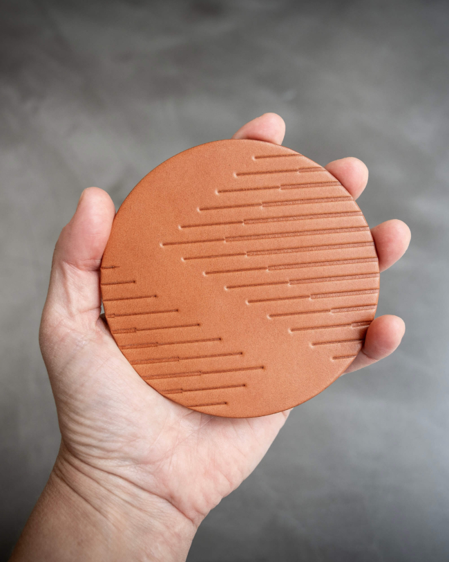 Tan leather coasters featuring modern stripe pattern debossed on the surface.
